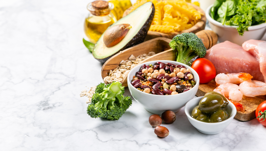 Polyphenol rich and Mediterranean food being down on a white table. Shrimp, nuts, broccoli, avocado and olives