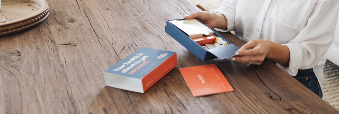 person opening up the personalized goode health blood test kit on a table