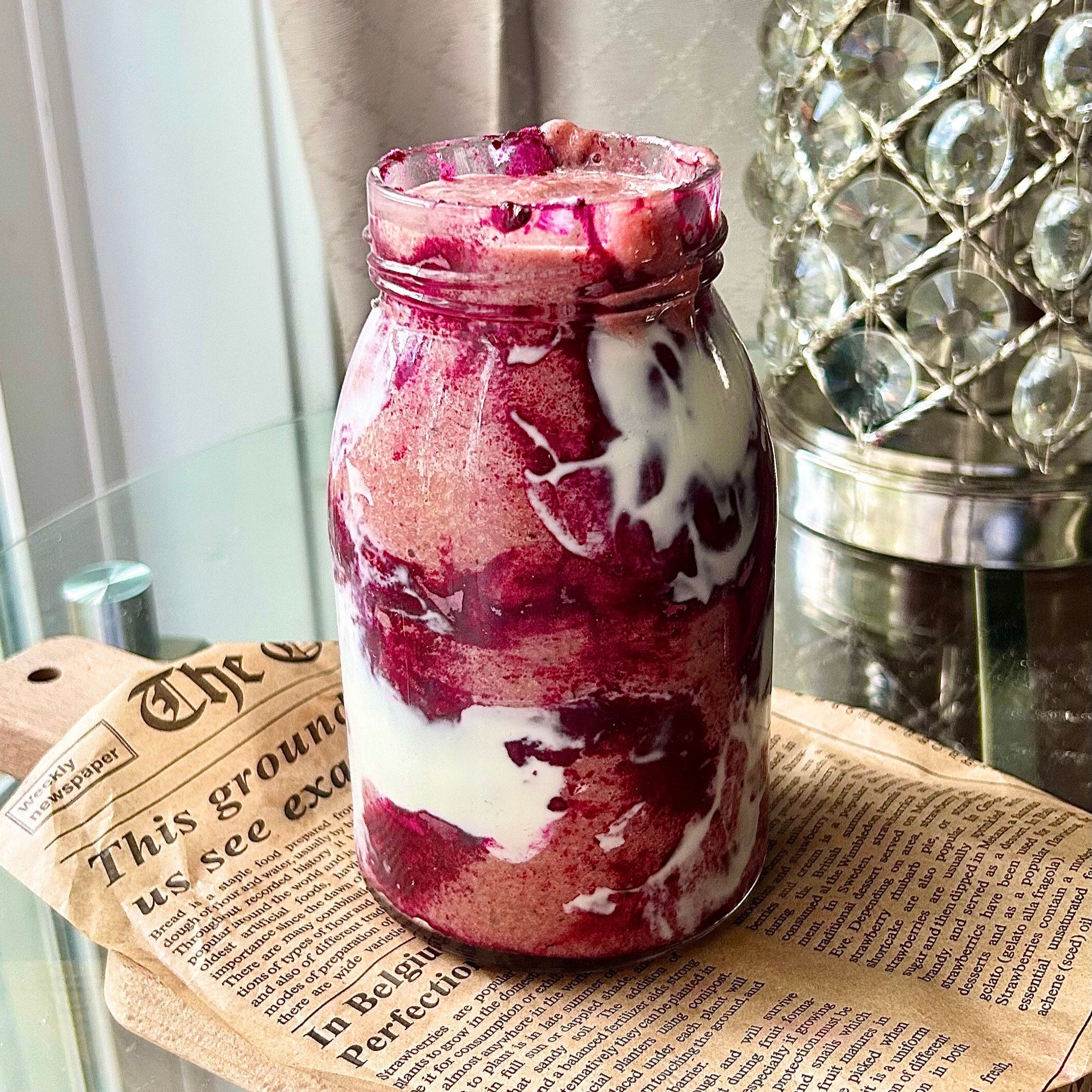 Goode Health Erewhon style smoothie in a glass jar on a newspaper surface, with a decorative lamp in the background. or Erewhon Style Smoothie