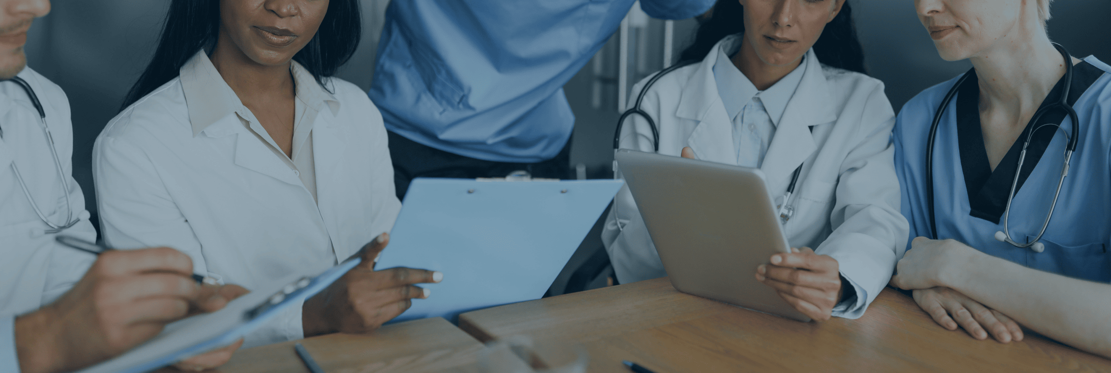 doctors huddled around a table with clip boards