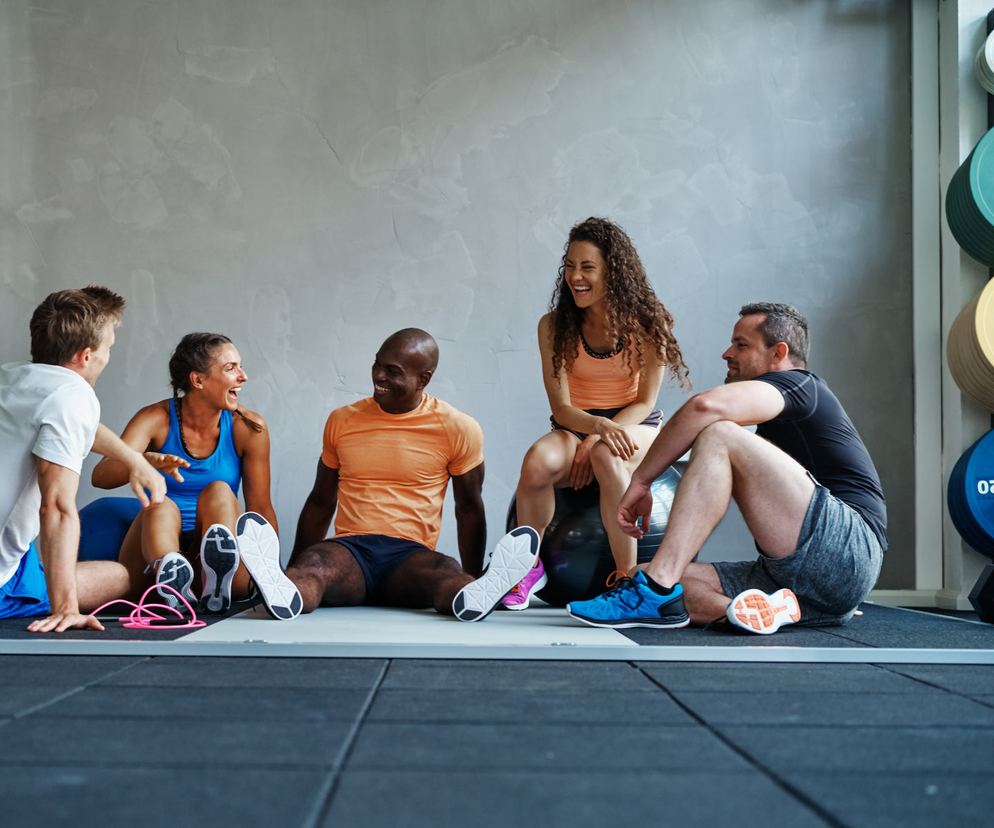 Fitness group sitting down and happily talking after a workout in a fitness studio