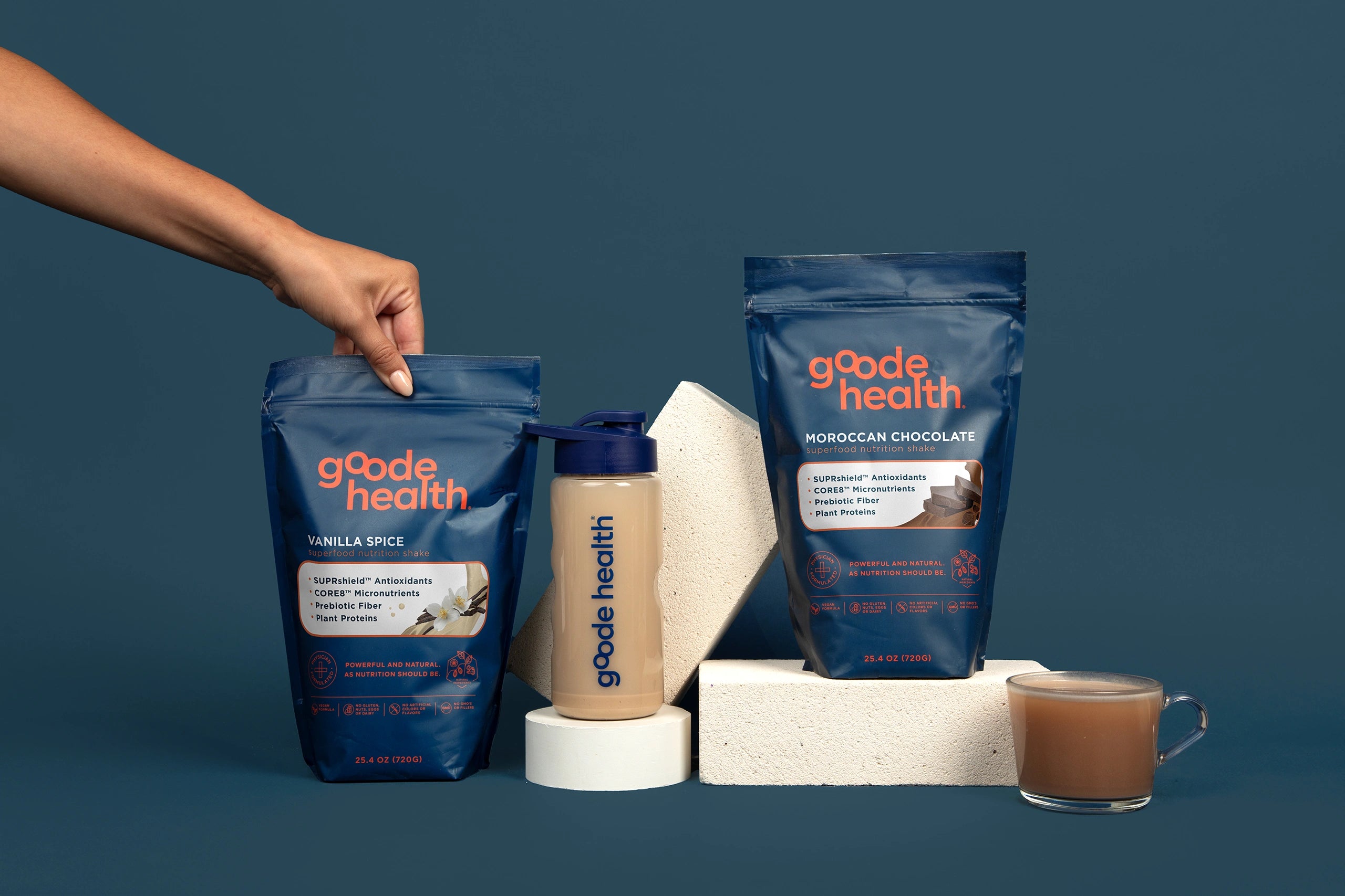 Image of Goode health products, shaker, mug, and a woman grabbing one bag