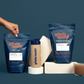 Image of Goode health products, shaker, mug, and a woman grabbing one bag